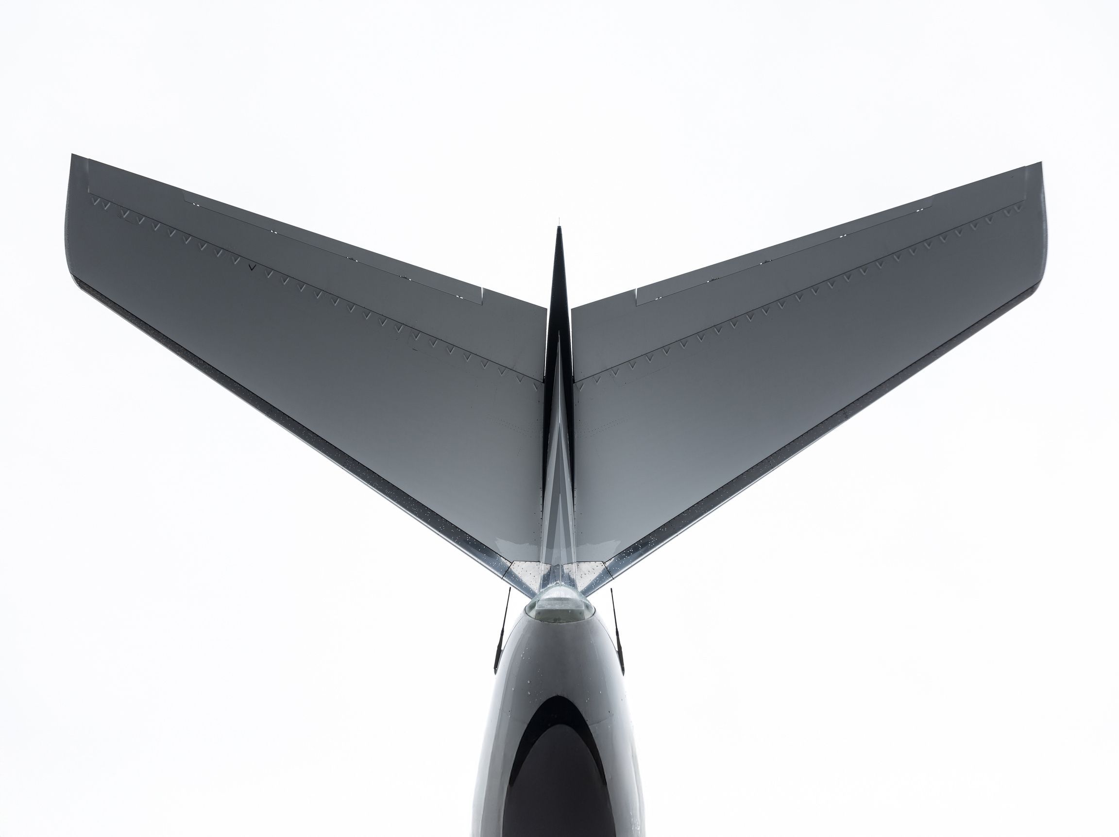 The tail of a private jet seen from below against a pale sky